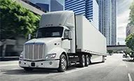 Peterbilt Model 579EV Electric White Truck Driving Through City - Thumbnail