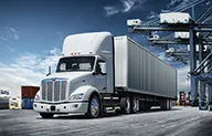Peterbilt Model 579EV Electric White Truck Driving Under Beams on Highway - Thumbnail